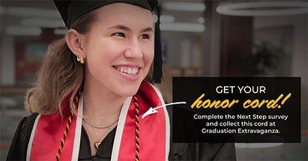 female student dressed in graduation attire smiling